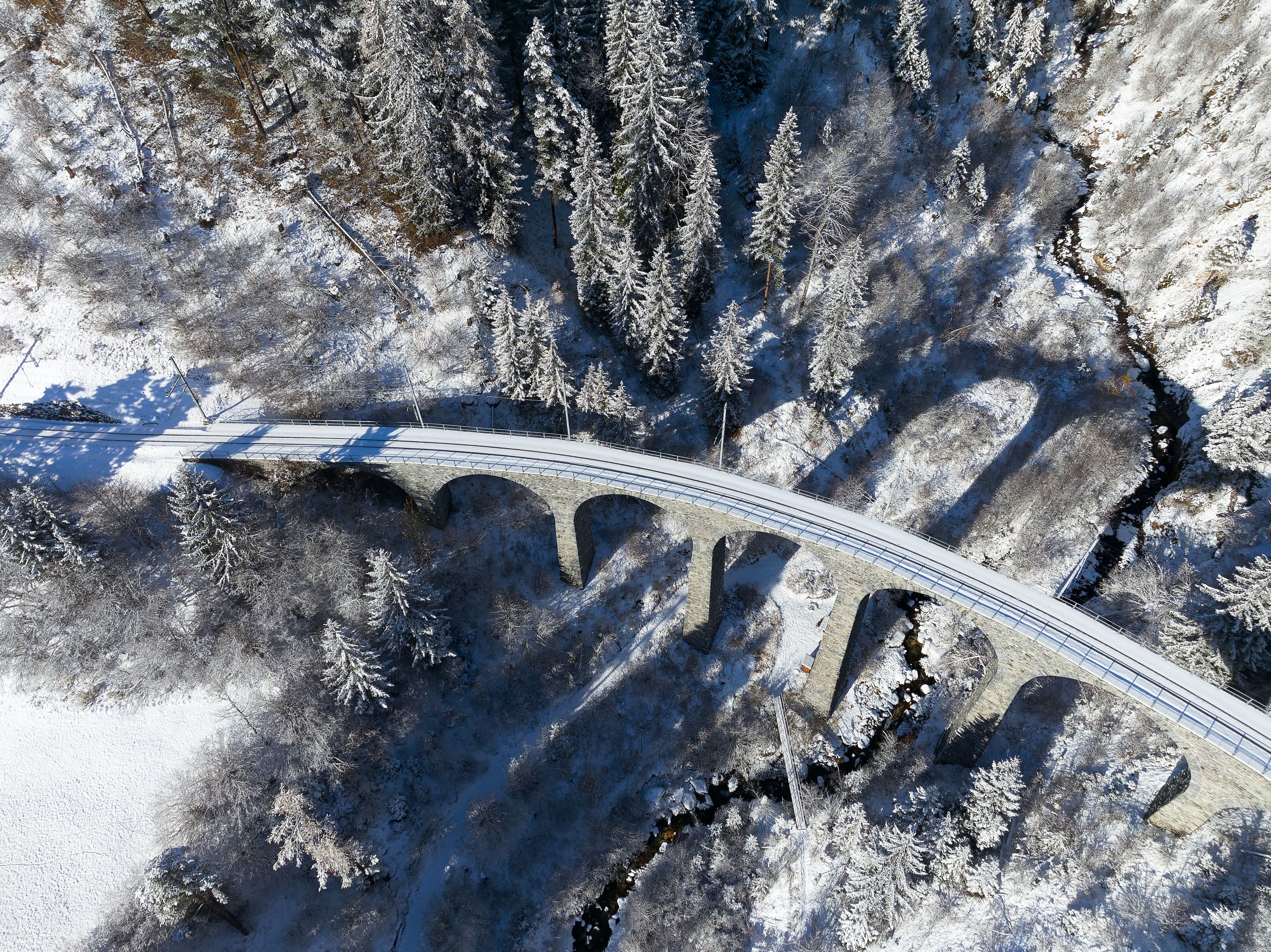 Aerial view of famous Schmittentobel Viaduct Unesco world heritage site in the Swiss Alps at mountain village of Filisur on a snowy autumn day. Photo taken November 22nd, 2024, Schmitten, Switzerland.