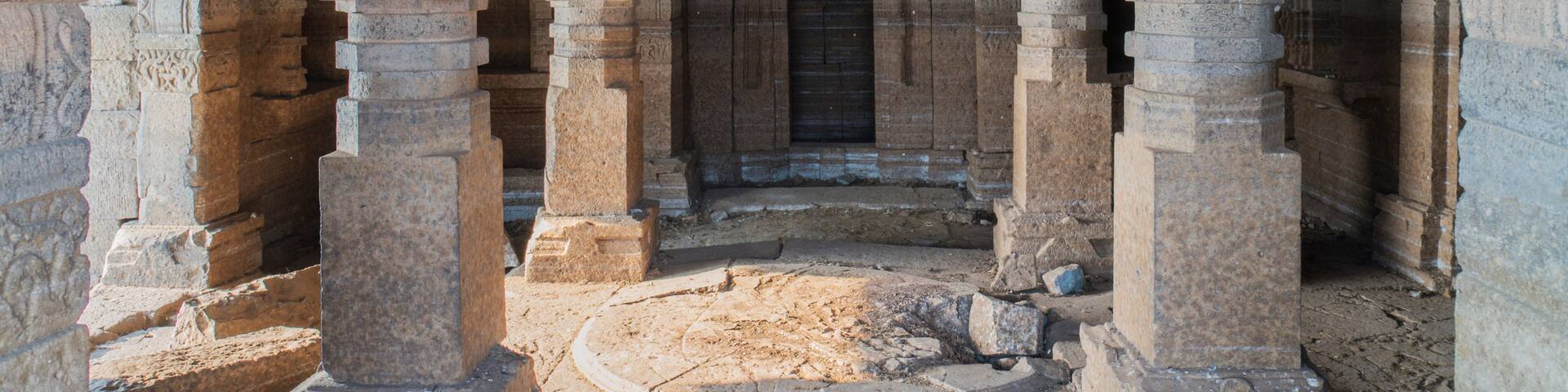An ancient stone structure with columns and a door.