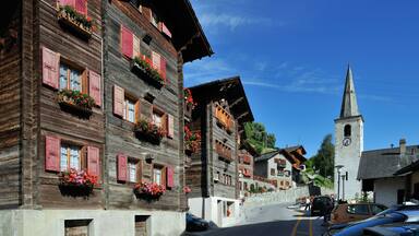 BGPE8P Church and traditional wooden houses / chalets decorated with geraniums in the Alpine village Saint-Martin, Valais, Switzerland