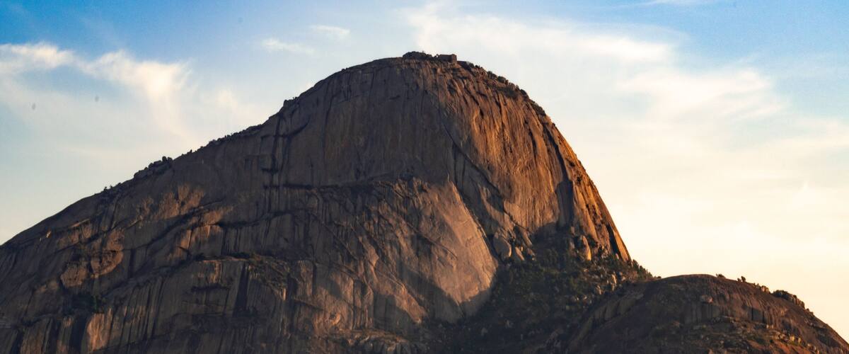 A large, rugged mountain with a steep, rocky surface and a flat top.