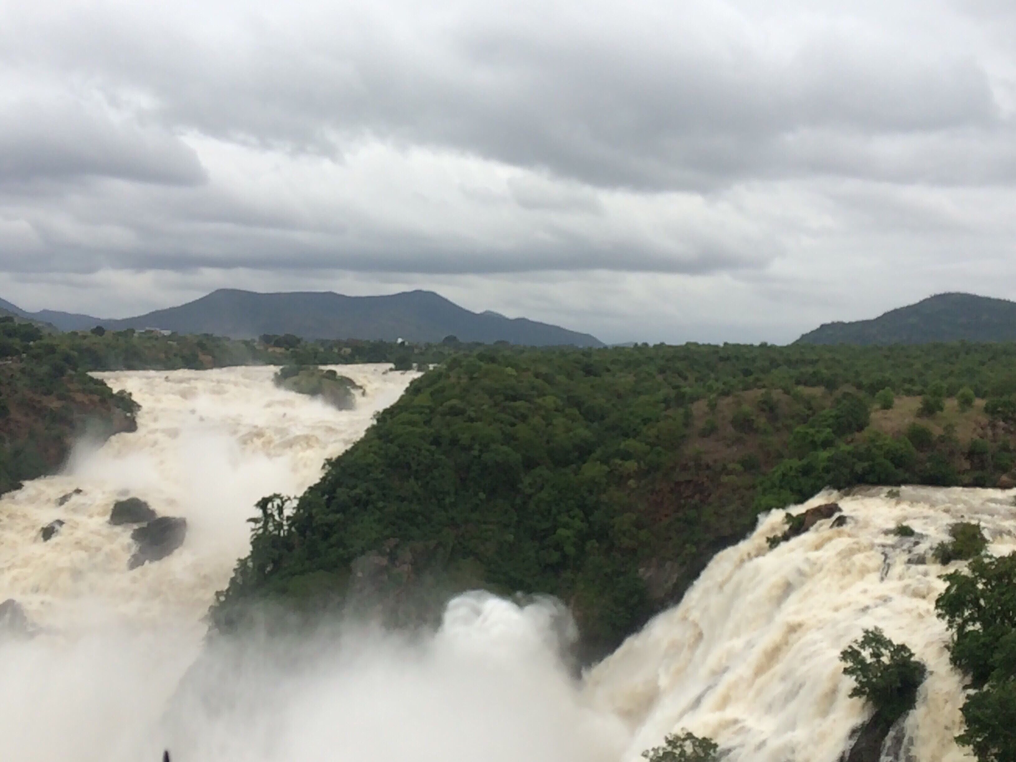 A powerful waterfall cascading down a lush, green valley surrounded by mountains.