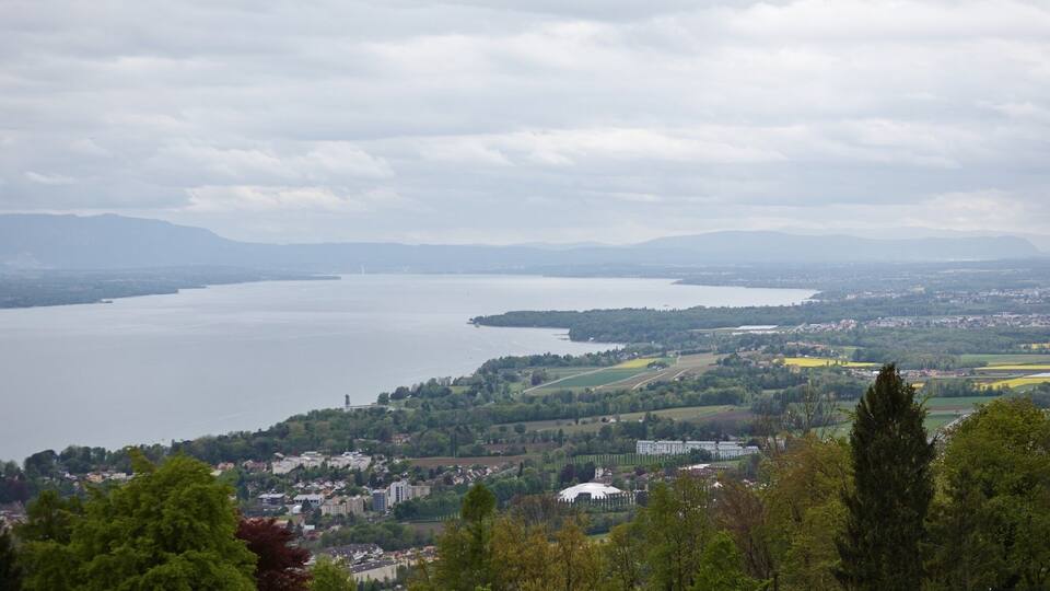 A panoramic view of a lake surrounded by mountains and a town.