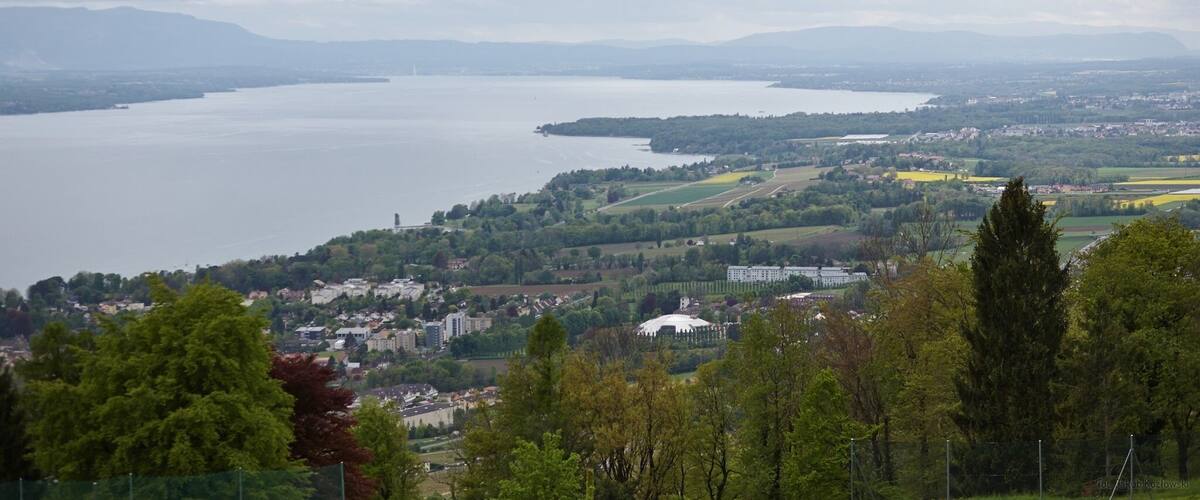 A panoramic view of a lake surrounded by mountains and a town.