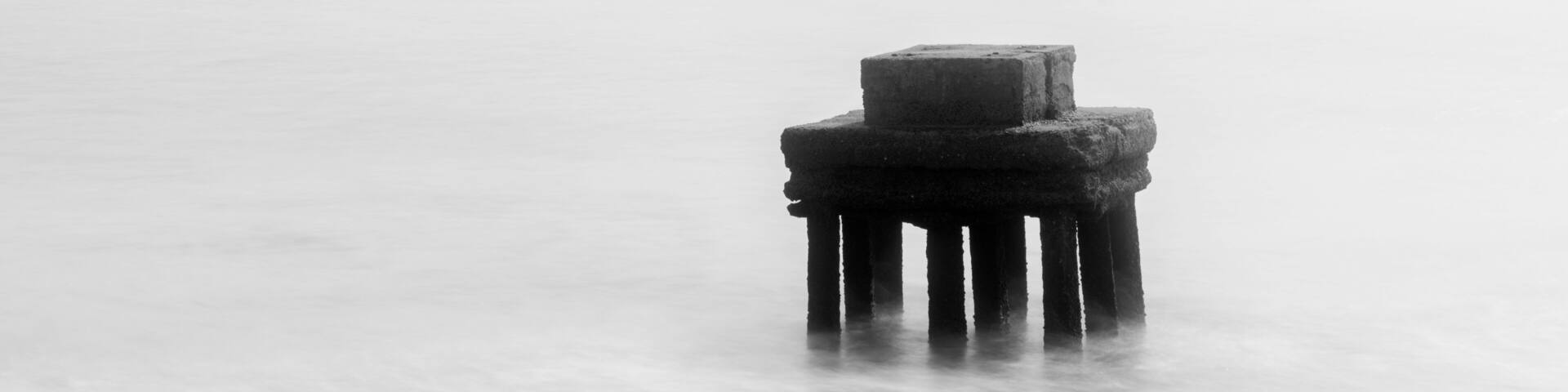 A solitary pier extending into a calm body of water.