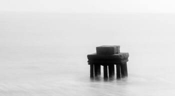 Un muelle solitario que se adentra en una superficie acuática tranquila.