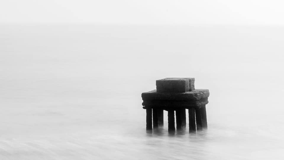 A solitary pier extending into a calm body of water.