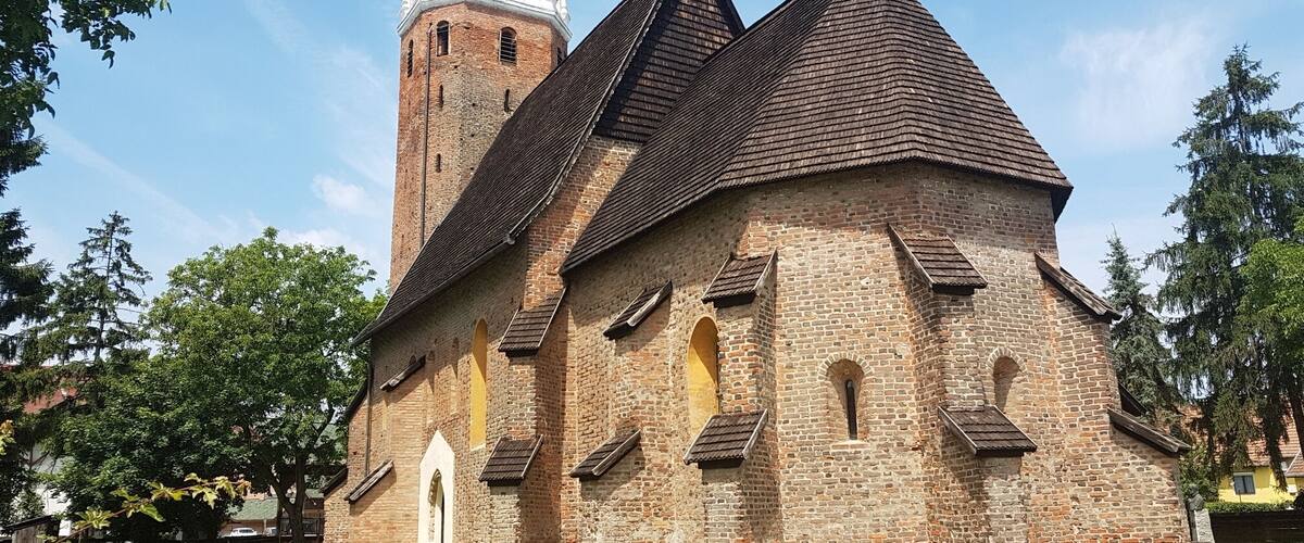 A historic church with a tall bell tower and a steeply pitched roof.