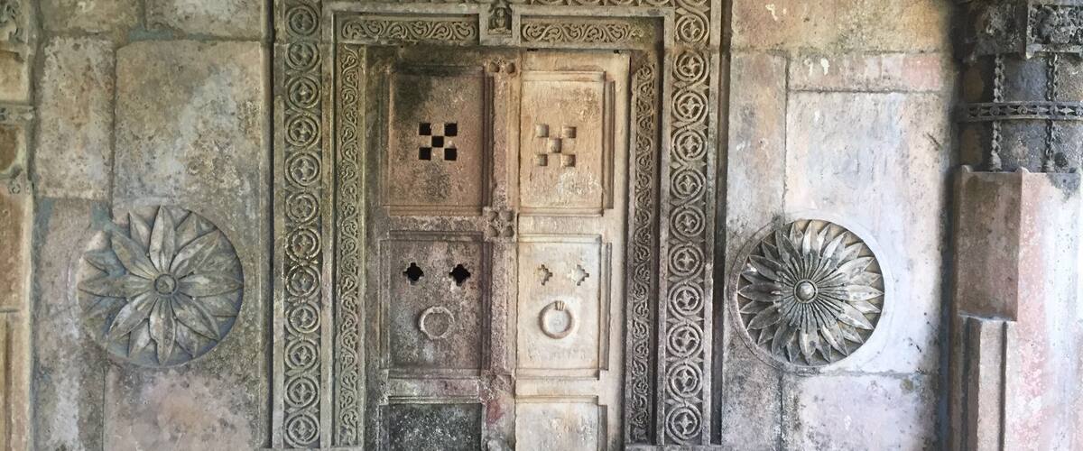 An intricately carved door with geometric patterns and a circular motif on either side.