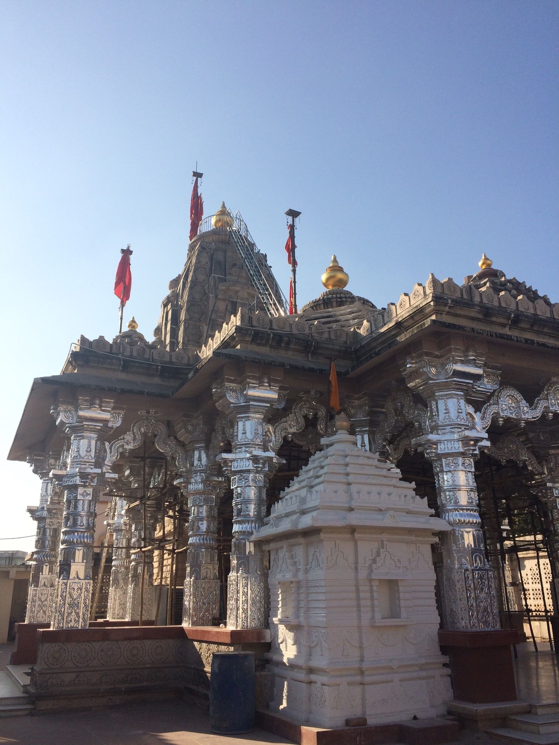 A temple with intricate carvings, a golden dome, and red flags.