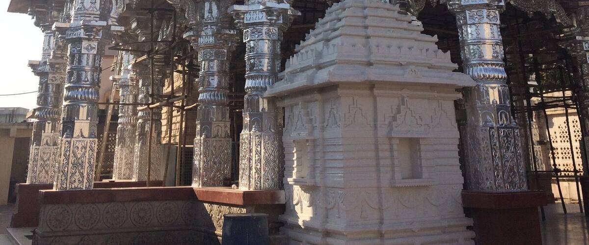 A temple with intricate carvings, a golden dome, and red flags.