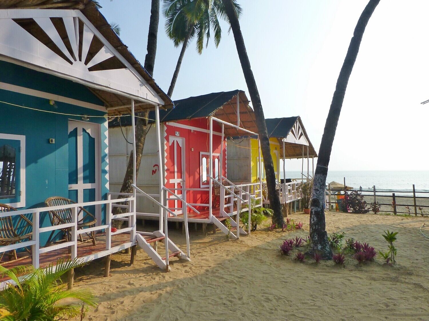 A beachside resort with colorful cabins and palm trees.