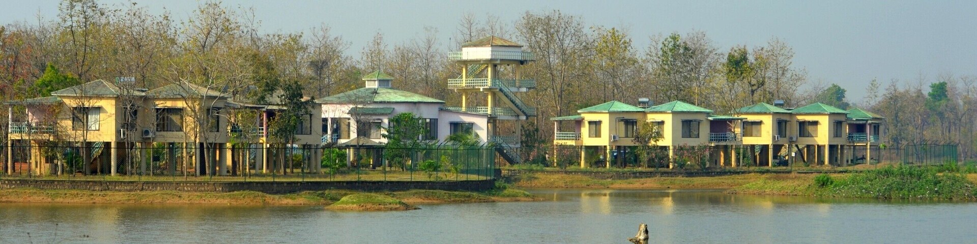 A lakeside resort with multiple buildings, a central tower, and a calm water body.