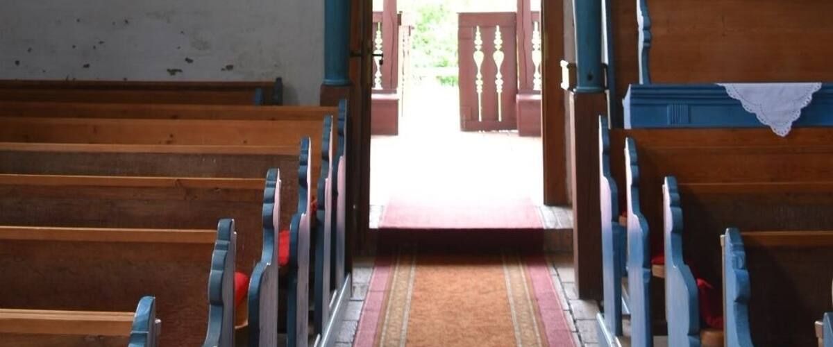 An interior with a patterned ceiling, blue walls, and a wooden bench area.