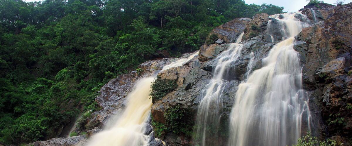 A multi-tiered waterfall surrounded by lush greenery.