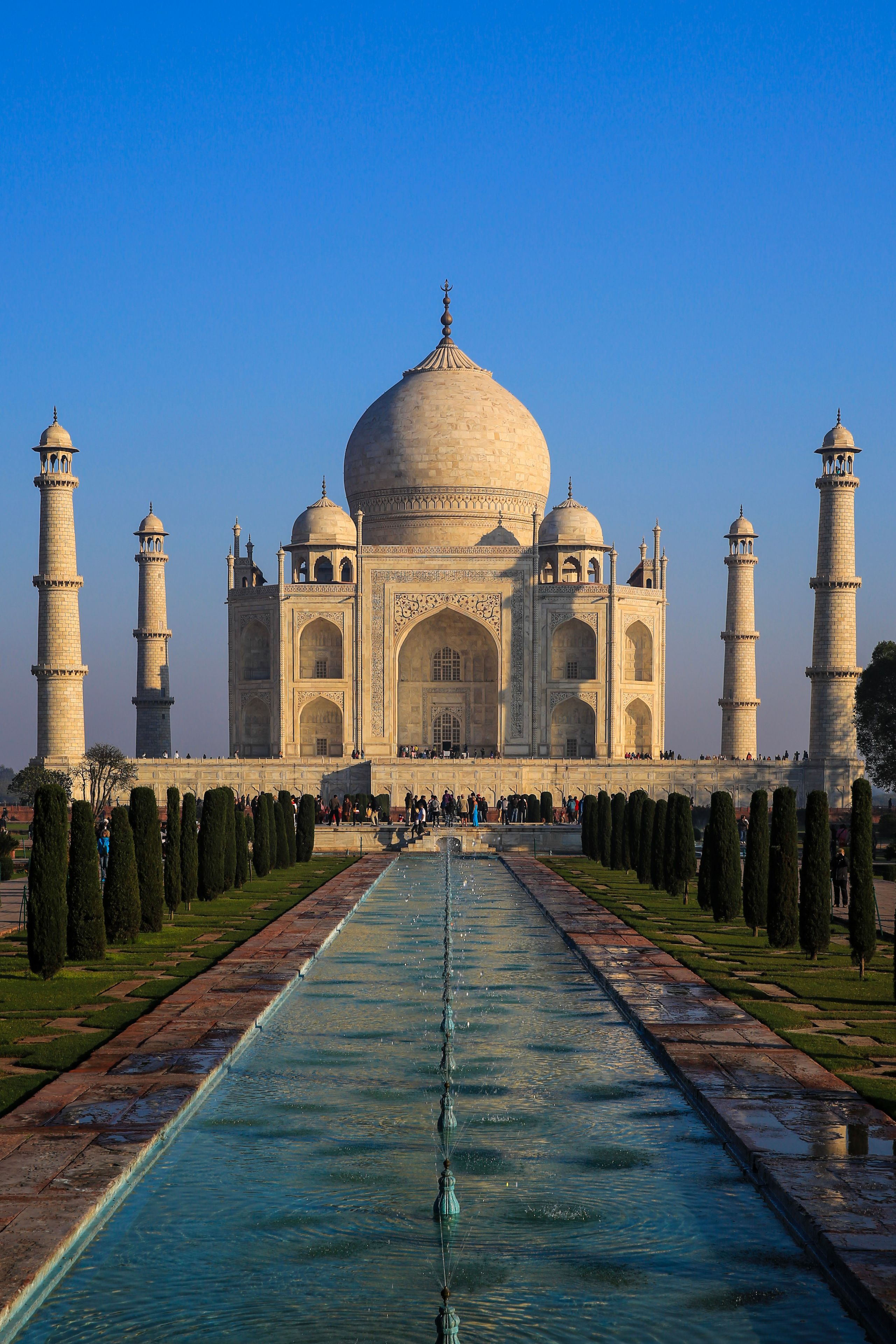 Taj Mahal, jossa on neljä minareettia, suuri kupoli ja pitkä, vettä heijastava allas.