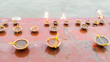 A row of clay lamps with flames, placed on a wet surface.