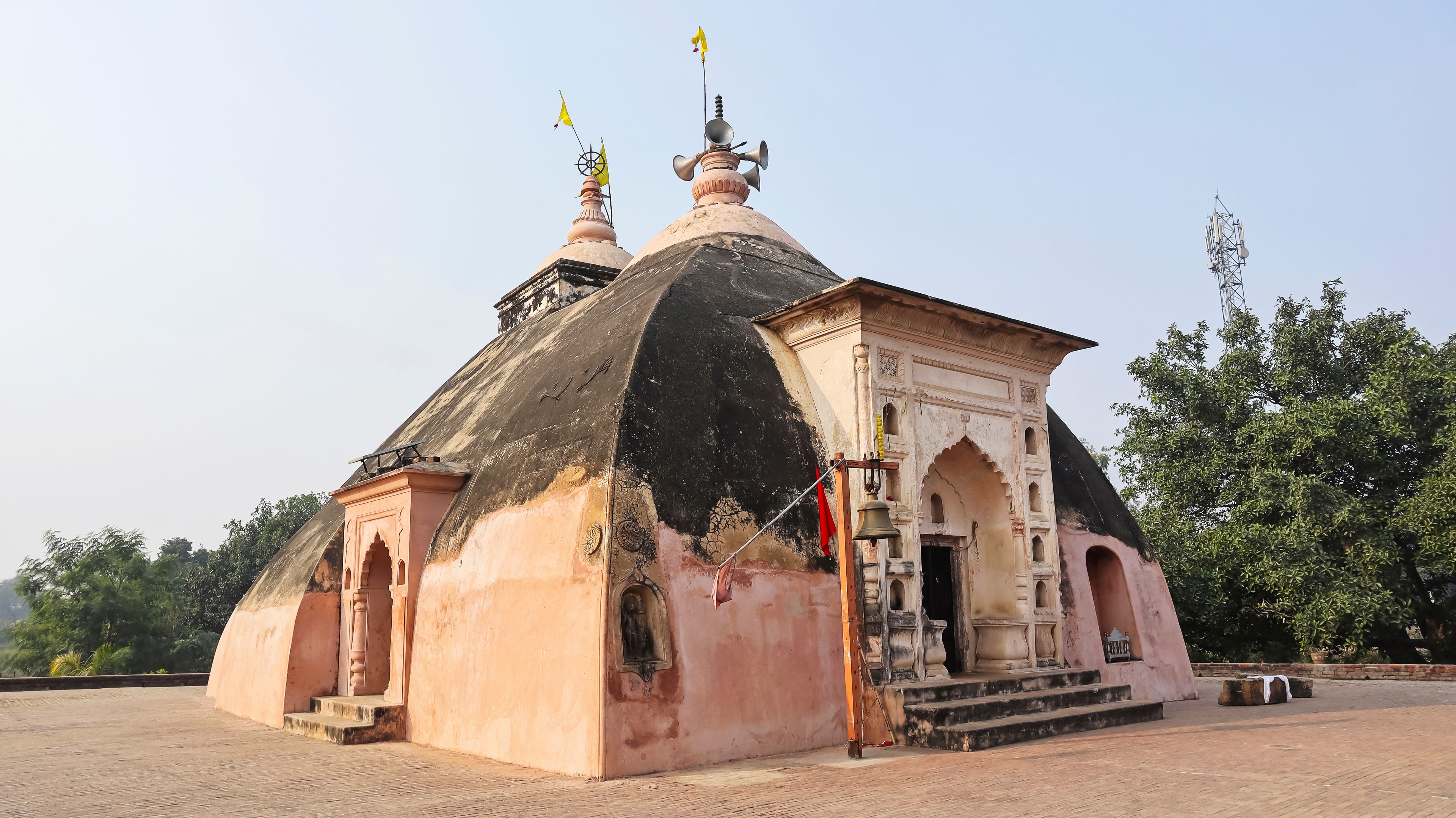 A small temple with a domed roof, a bell tower, and a flag on top.