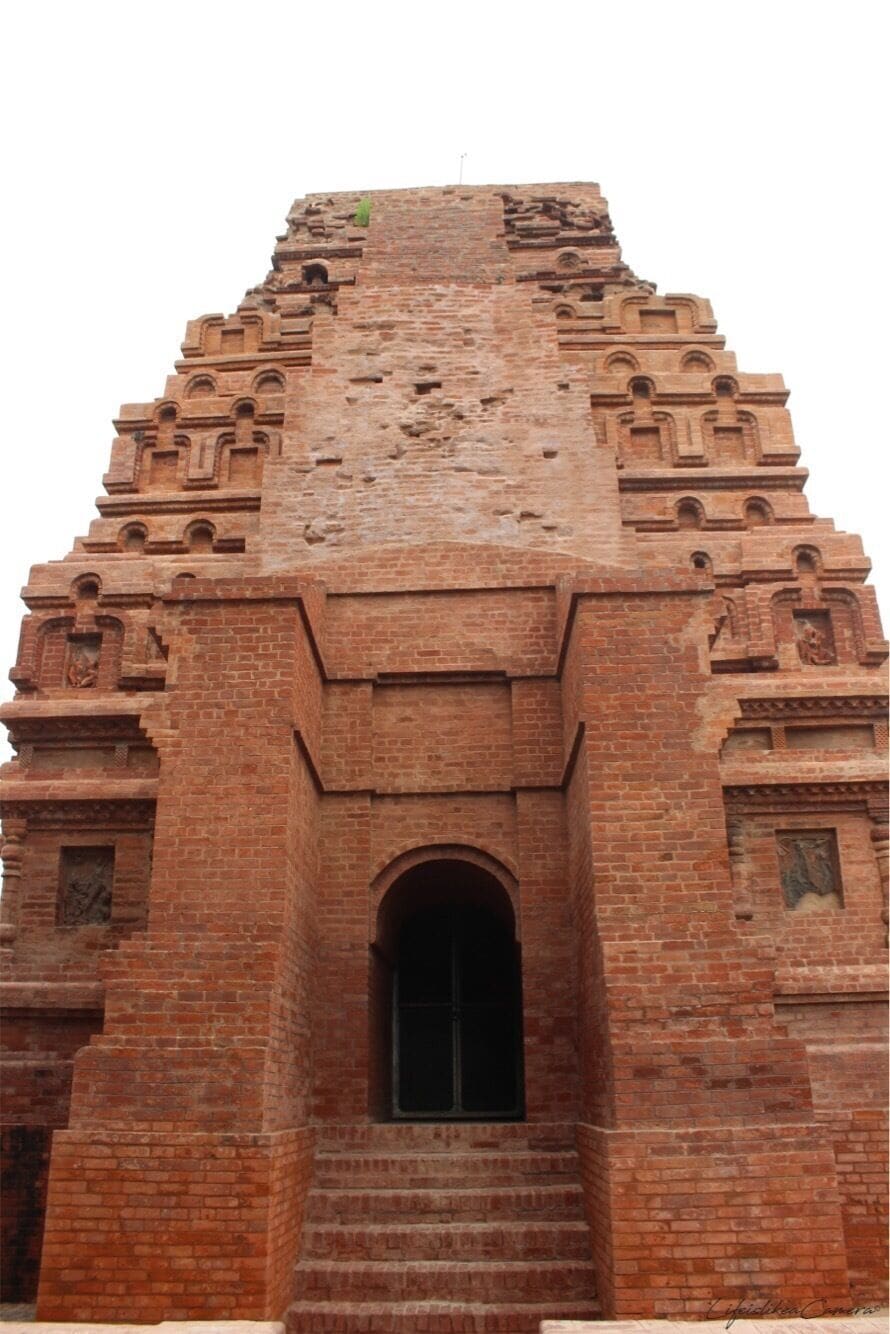 A large, ancient brick structure with a central arched doorway and intricate carvings.