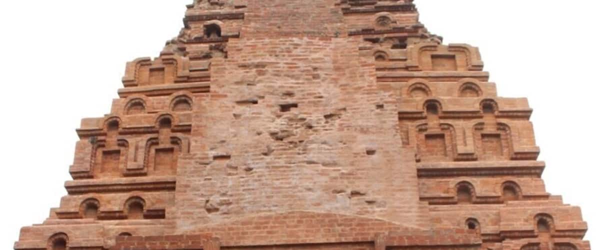 A large, ancient brick structure with a central arched doorway and intricate carvings.