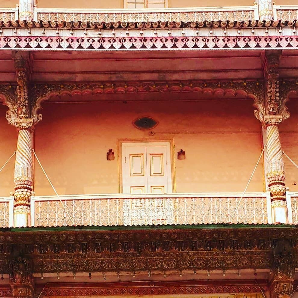 A traditional building with ornate balconies, detailed carvings, and a prominent door.