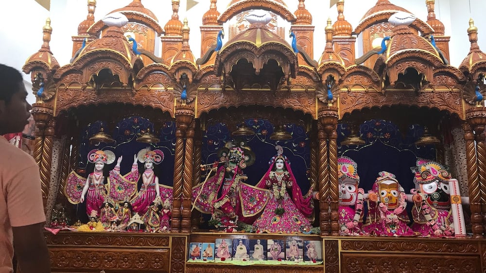 A temple with ornate wooden structures, multiple deity statues, and intricate carvings.