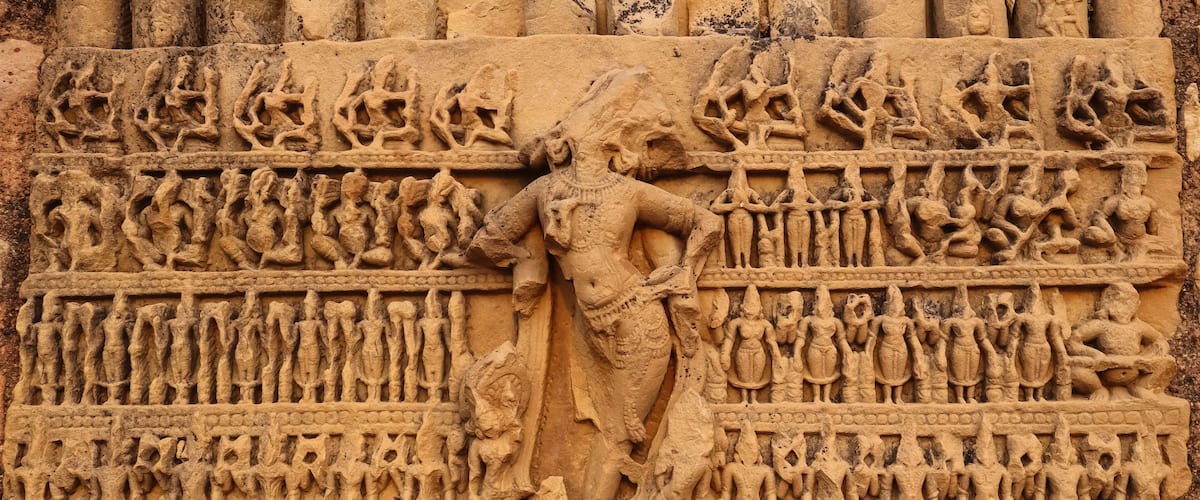 A detailed stone carving with a central figure and multiple rows of figures, likely depicting a historical or mythological scene.
