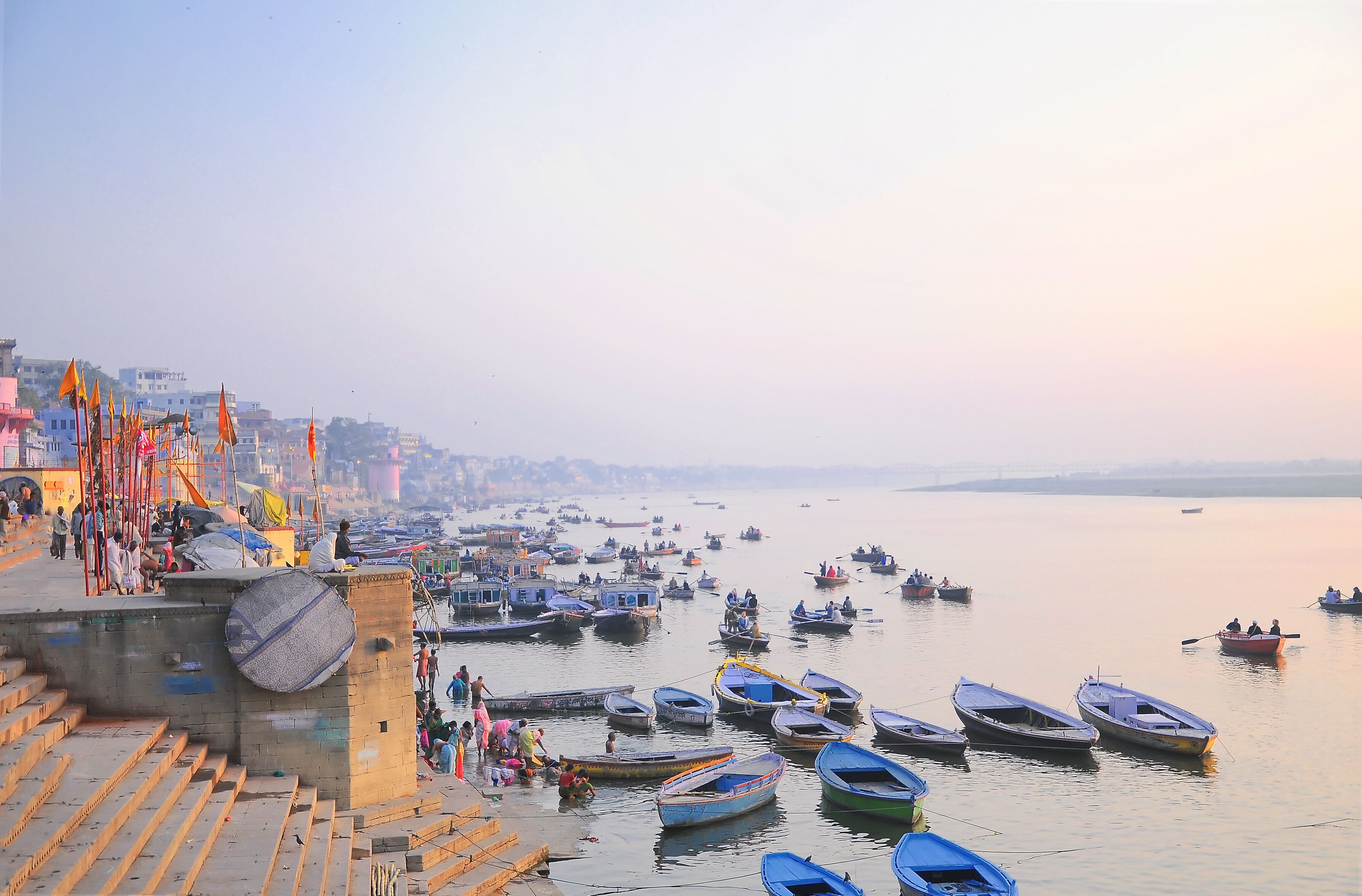 A riverside with boats docked and people walking along the steps.