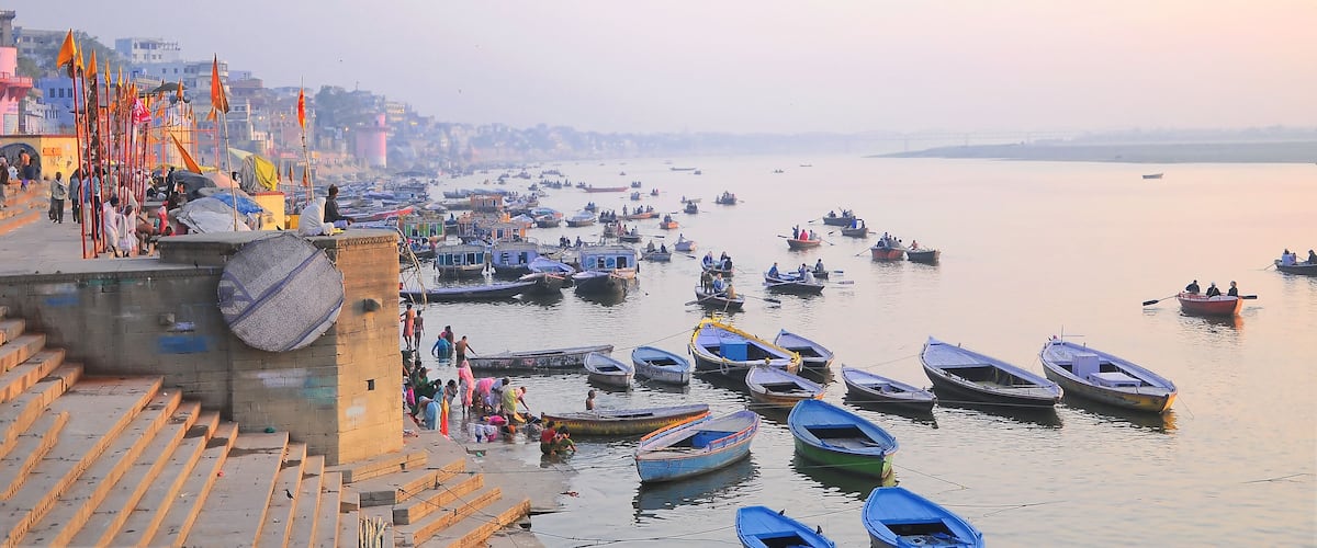 A riverside with boats docked and people walking along the steps.