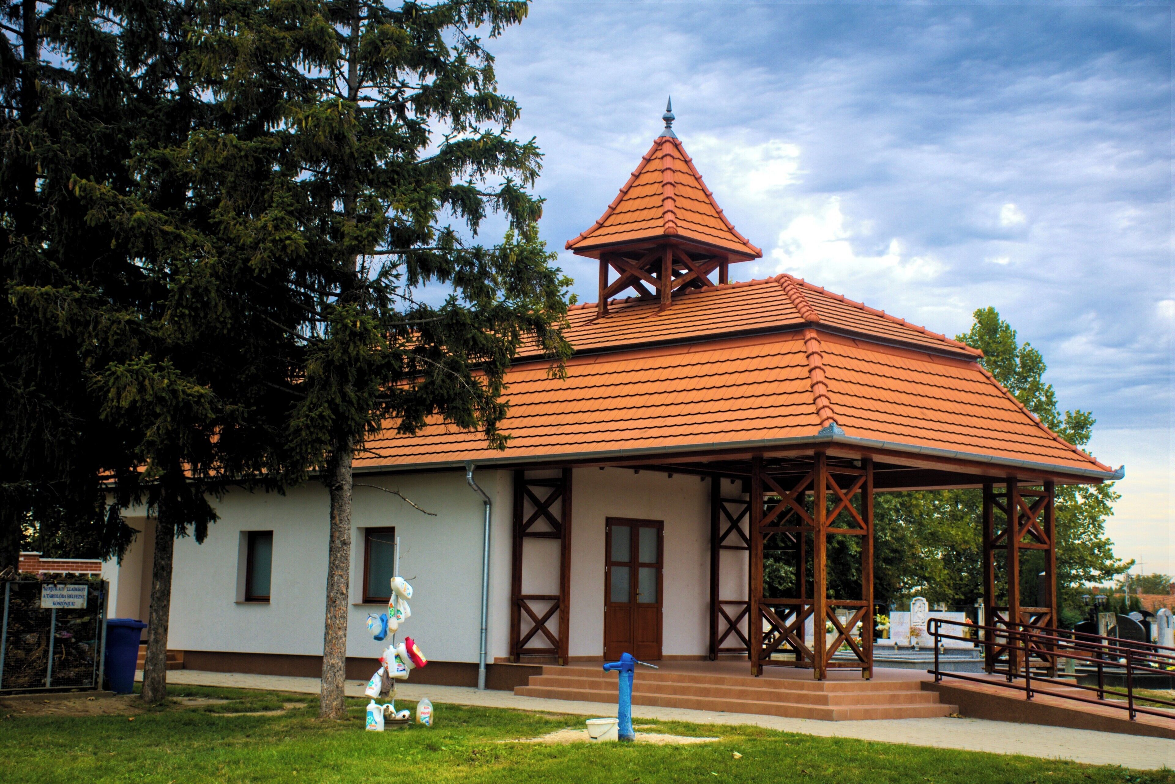 A small building with a red-tiled roof and a wooden pavilion.