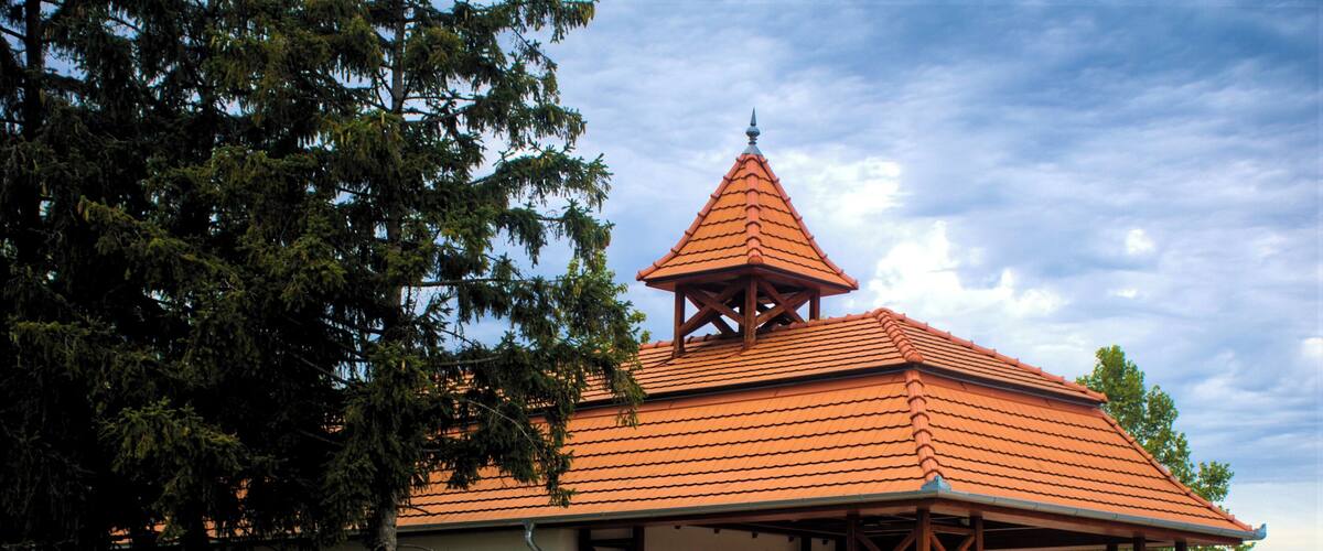 A small building with a red-tiled roof and a wooden pavilion.