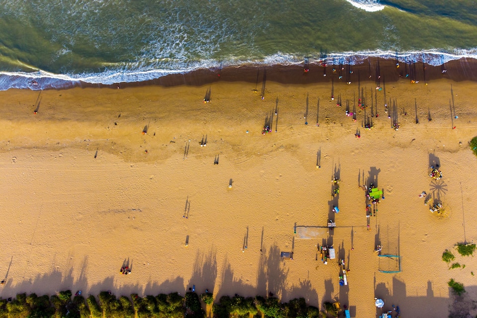An aerial view of a beach with people, tents, and a lifeguard tower.
