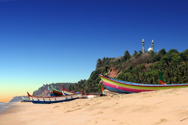 panoramic view of colorful fishermen boats in front of Varkala South Cliff with mosque on top, Kerala, India