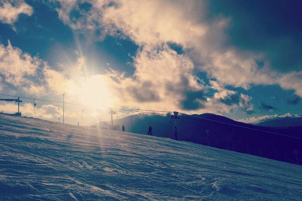 A snowy ski slope with a ski lift and a mountain in the background.