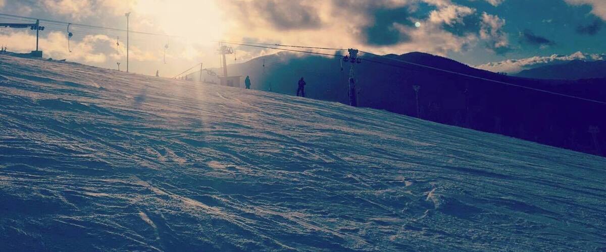 A snowy ski slope with a ski lift and a mountain in the background.