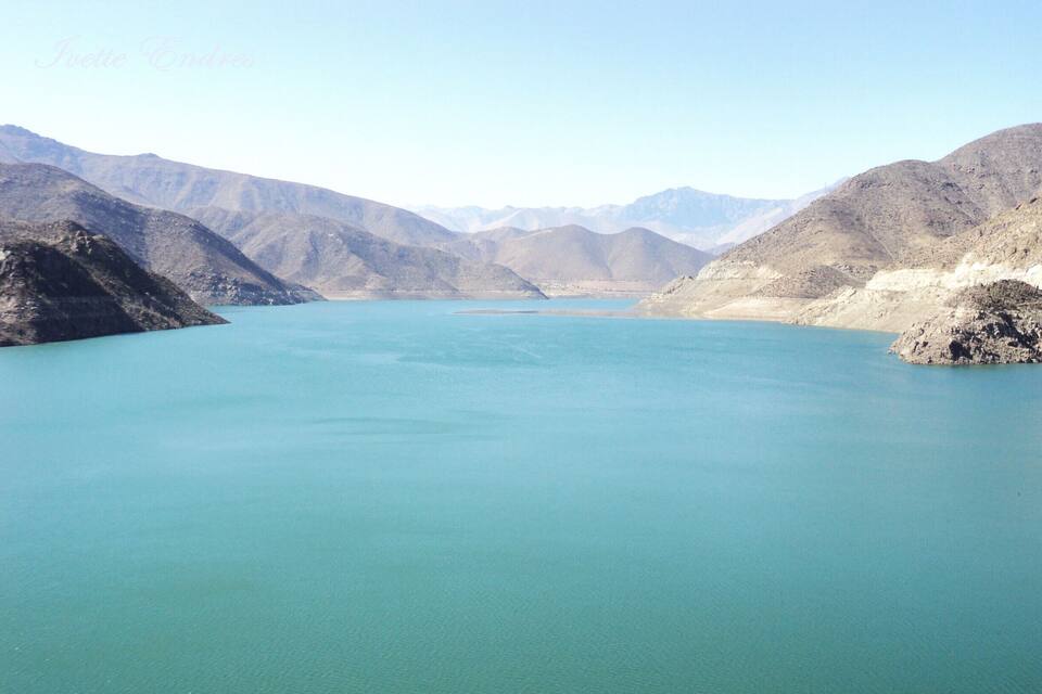 Un extenso cuerpo de agua turquesa rodeado de montañas escarpadas.