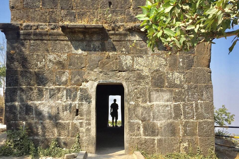 A stone building with a doorway and a silhouette of a person inside.