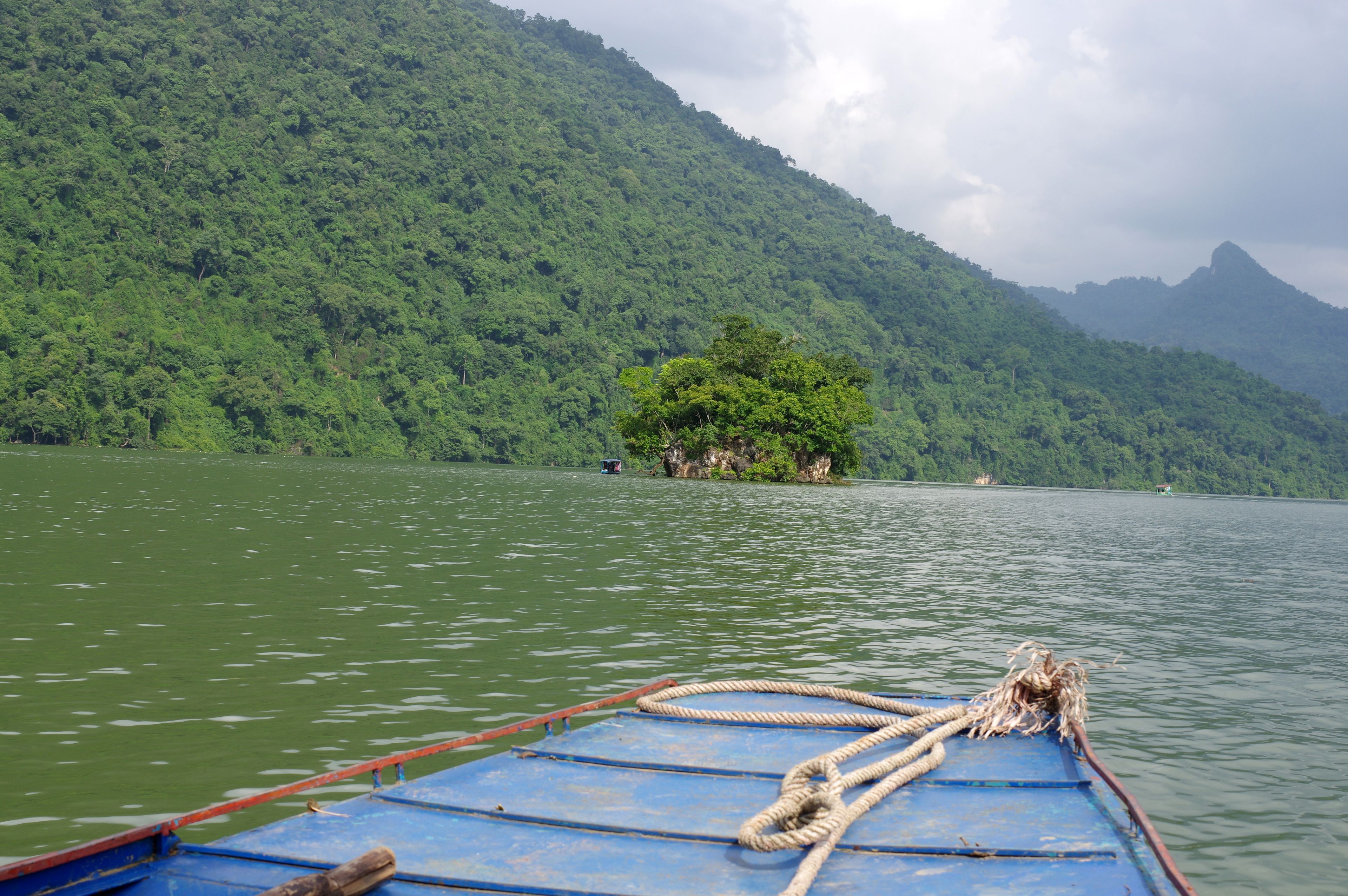 Un barco en un lago tranquilo con una montaña boscosa al fondo.