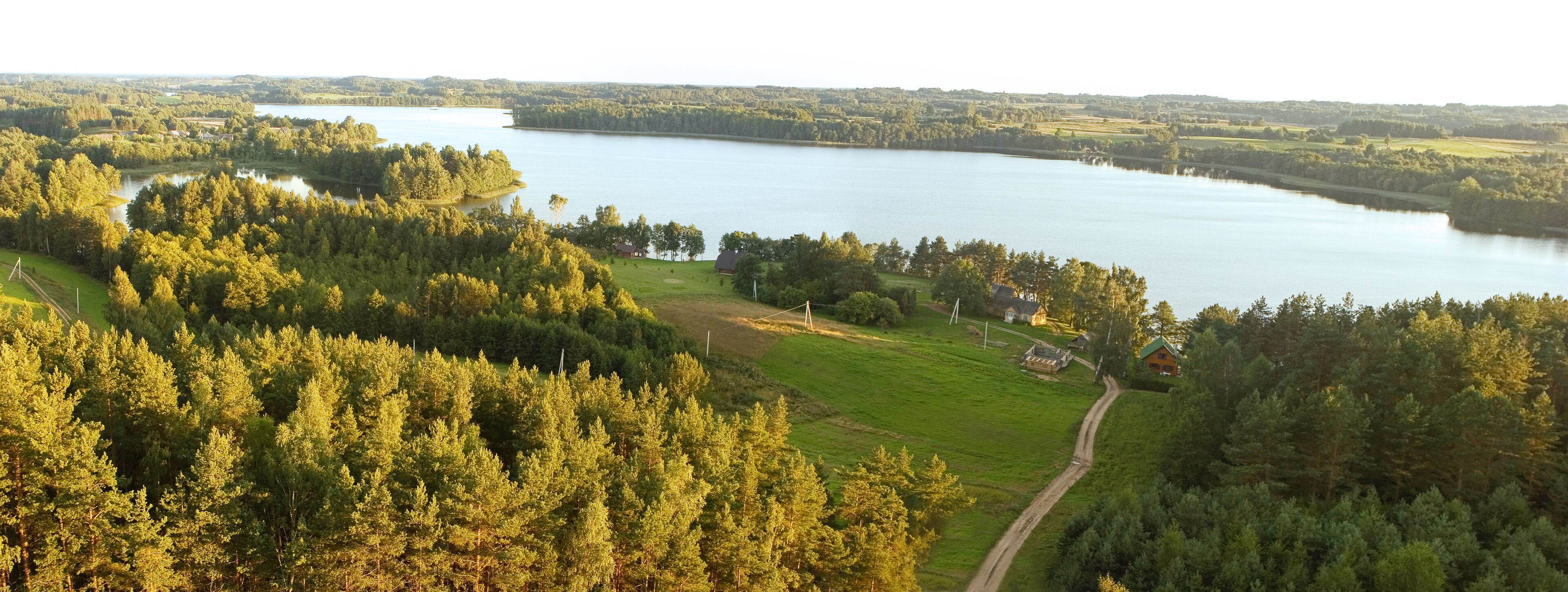 A lake surrounded by dense forests and a few houses.