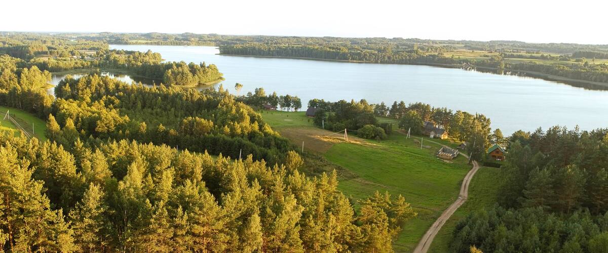 A lake surrounded by dense forests and a few houses.