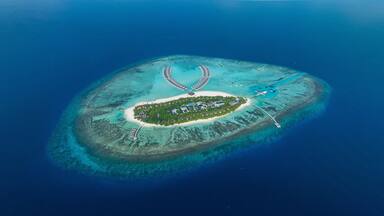 Aerial view of Kuredhivaru Island with luxury resort and beautiful turquoise beach, Noonu Atoll, Maldives.