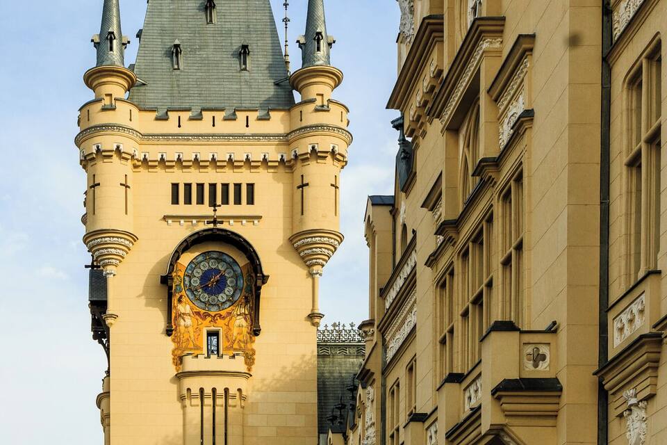 A historic building with a clock tower, ornate architectural details, and a clear blue sky.