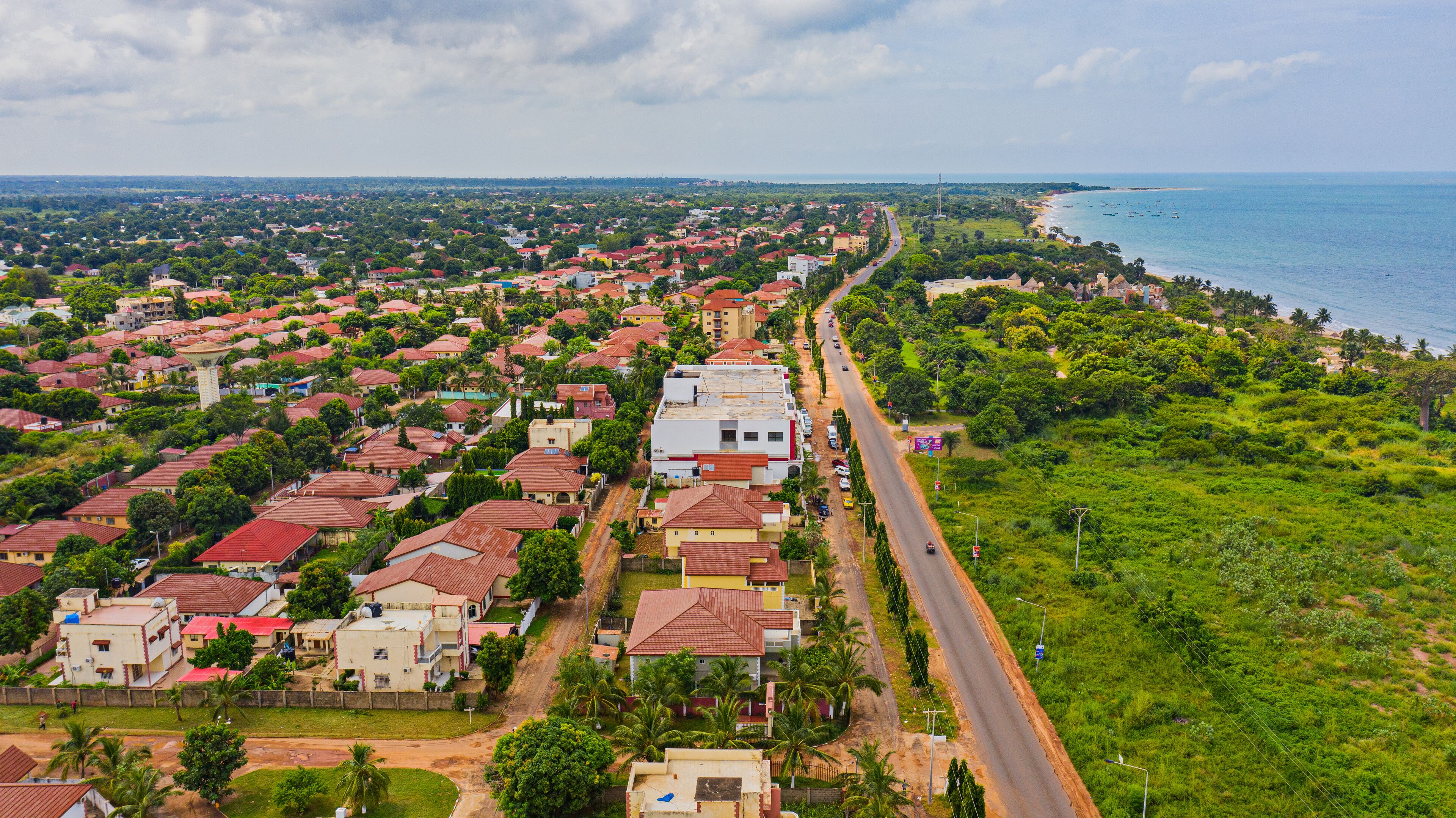 A coastal town with red-roofed houses, a beach, and a road leading to the sea.