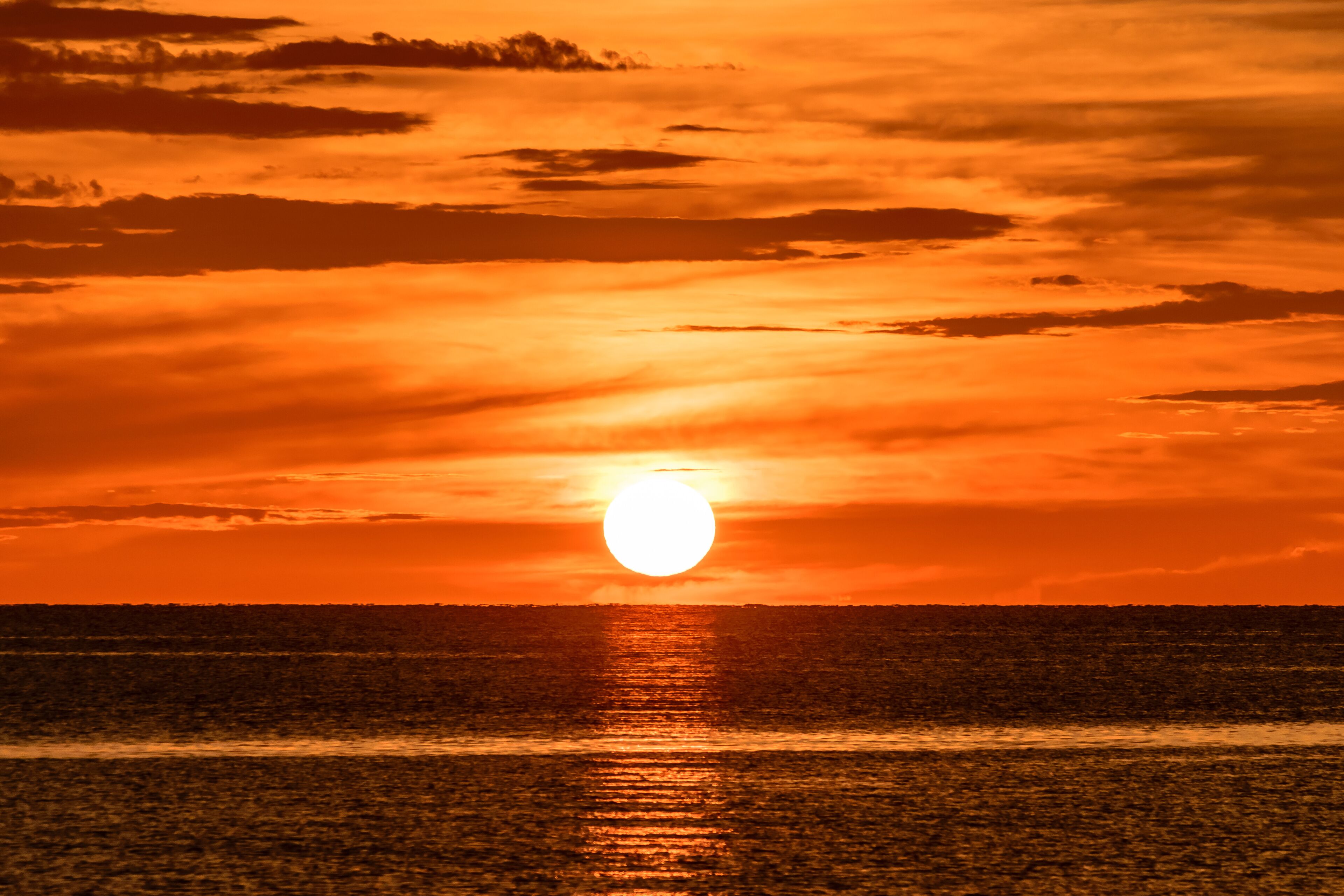 A sunset over a calm sea with a visible horizon line.