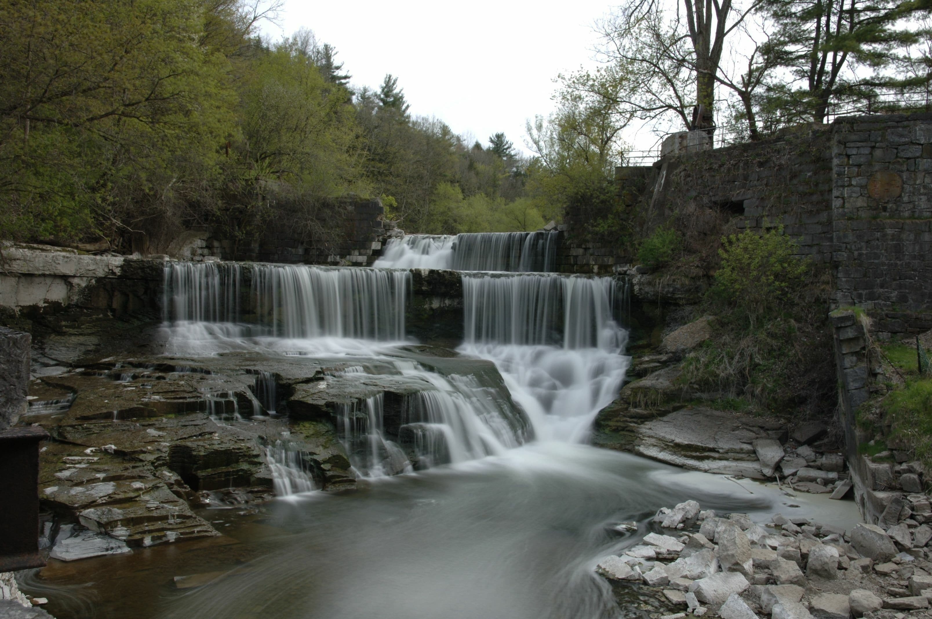 Vertical shot of Keuka Lake Outlet Trail with green trees and an old building around it