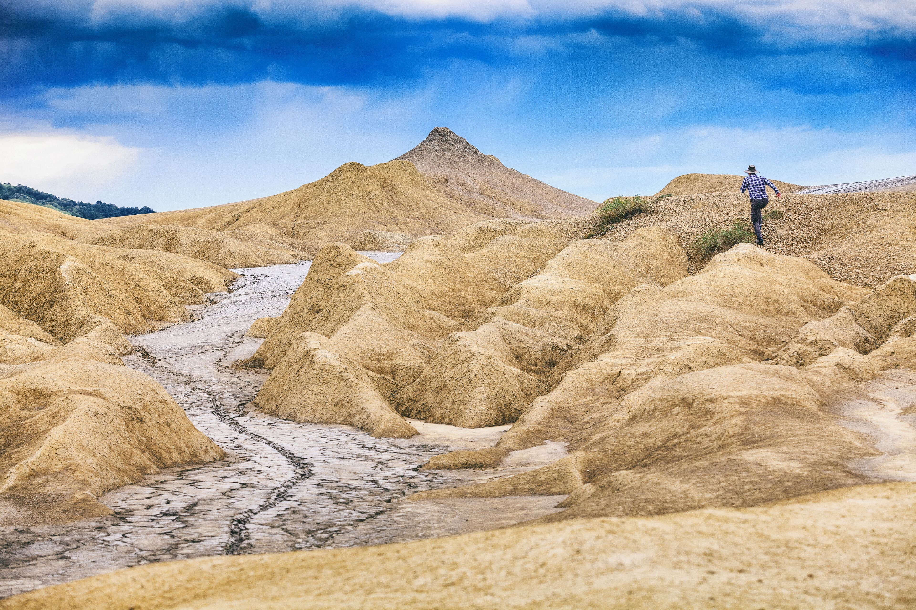 A person standing on a sandy hill with a river flowing through a dry landscape.