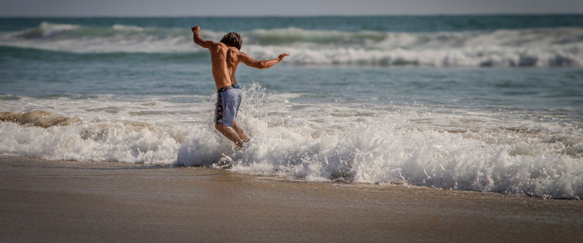 A person surfing on a beach with waves crashing onto the shore.