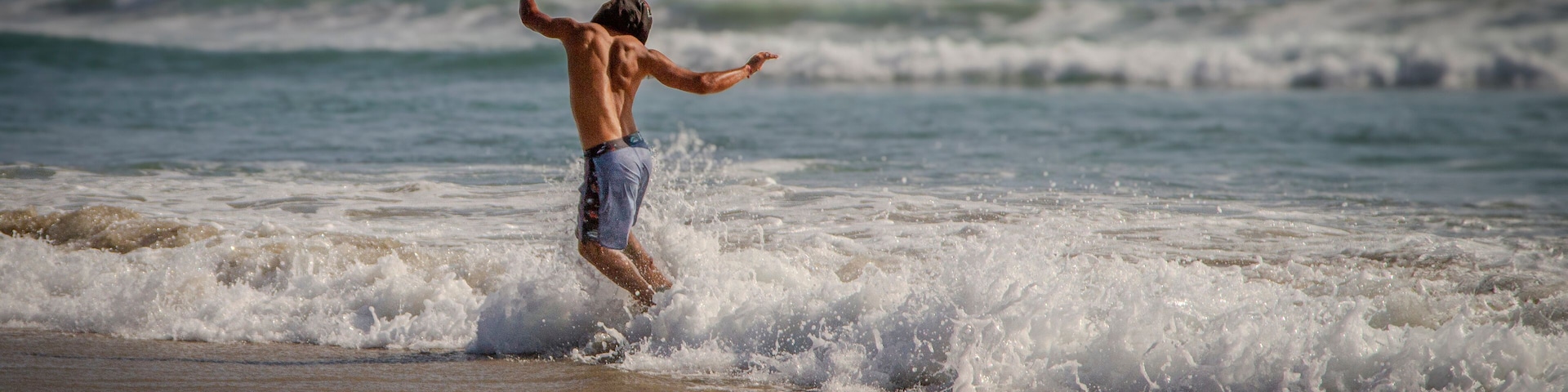 A person surfing on a beach with waves crashing onto the shore.