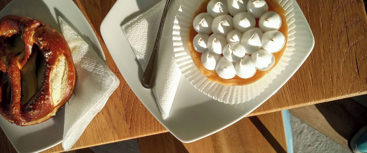 A plate of pretzels and a plate of marshmallows on a wooden table.