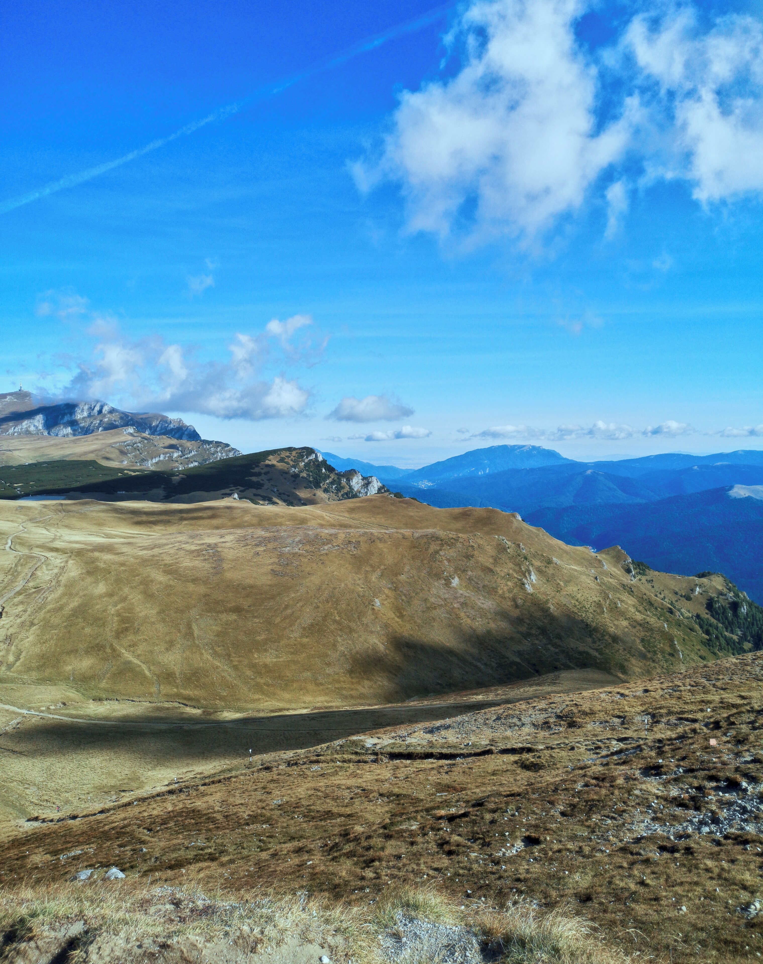 A mountainous landscape with a clear blue sky and distant mountain ranges.