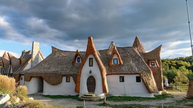 Une maison traditionnelle à toit de chaume, aux murs blancs et dotée d’une porte centrale.